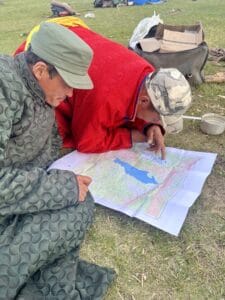 Two travelers studying a detailed map of Mongolia outdoors.