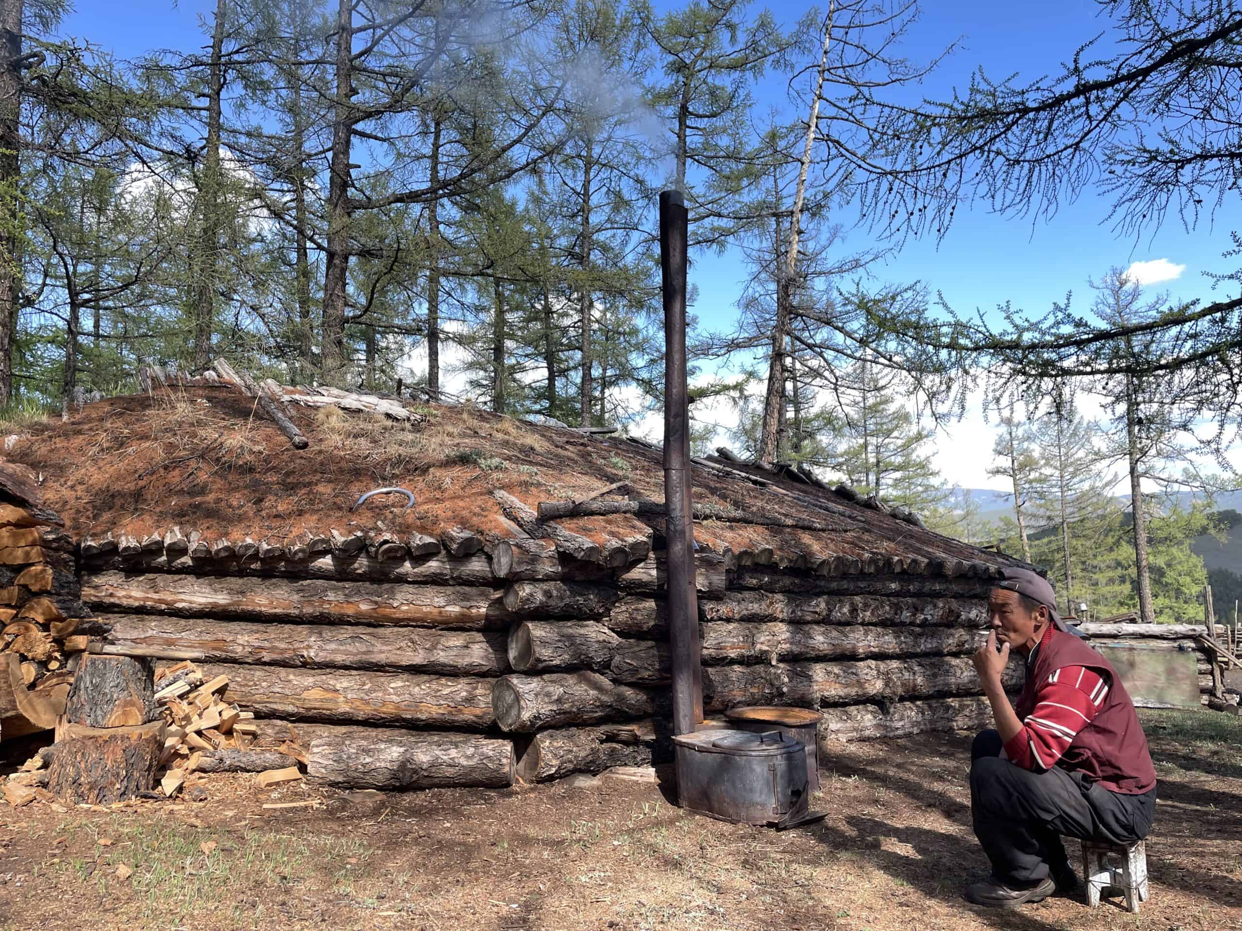 Traditional Mongolian ger with a person sitting nearby outdoors.