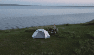 Camping tent and motorcycle near a tranquil lake in Mongolia.