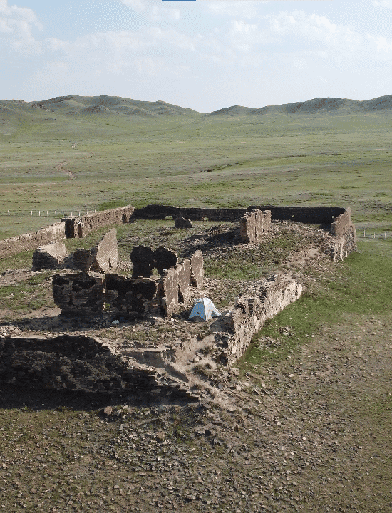 Ruins of ancient Mongolian structures in vast open steppe landscape.